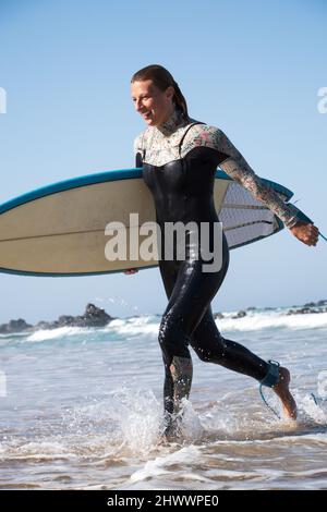 Happy caucasian surfer getting out of the ocean after catching waves Stock Photo