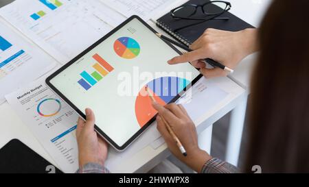 Close-up, Two accountants are looking at the information on the tablet screen, analysing and planning the monthly budget plan for the new campaign. Stock Photo