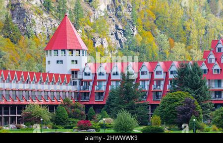 Beautiful landscape of a mountain and lake with red buildings on a shore. Three Valley Gap Lake Chateau Hotel, BC, Canada-September 26,2021. Travel Stock Photo