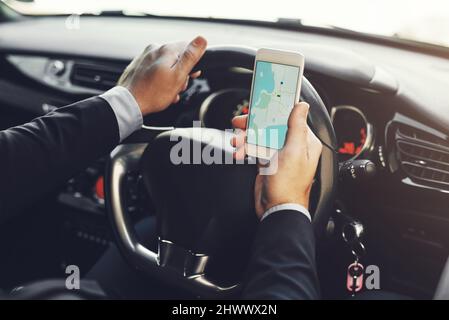 Getting around with the help of technology. Closeup shot of an unrecognizable businessman using his cellphone while driving. Stock Photo