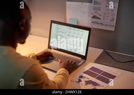 Close-up of African businessman working with document on laptop at his workplace, he making plan or project online working till night Stock Photo