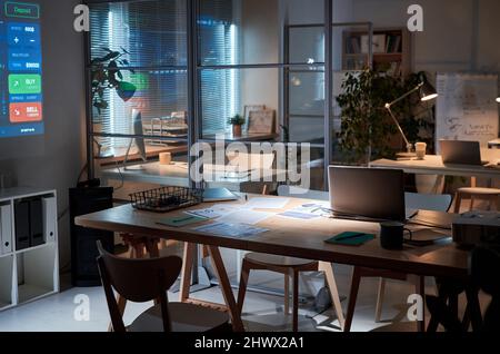 Image of workplace with documents and laptop on it in empty dark board room at office Stock Photo