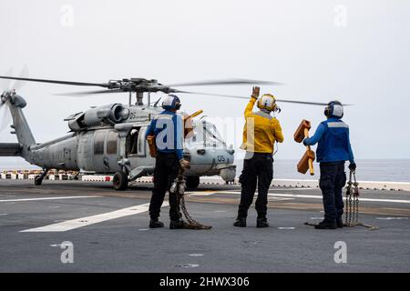 PHILIPPINE SEA (March. 4, 2022) Sailors assigned to the forward-deployed amphibious assault ship USS America (LHA 6) signal that chocks and chains were removed from an MH-60S Sea Hawk helicopter from Helicopter Sea Combat Squadron (HSC) 25 on the ship’s flight deck. America, lead ship of the America Amphibious Ready Group, along with the 31st Marine Expeditionary Unit, is operating in the U.S. 7th Fleet area of responsibility to enhance interoperability with allies and partners and serve as a ready response force to defend peace and stability in the Indo-Pacific region. (U.S. Navy photo by Mas Stock Photo