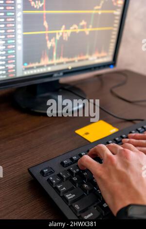 Man's hands on the desktop computer keyboard analyzing the stock market and cryptocurrencies with a credit card ready to buy if an opportunity appears Stock Photo