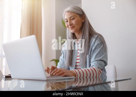 Joyful woman working on notebook at home Stock Photo