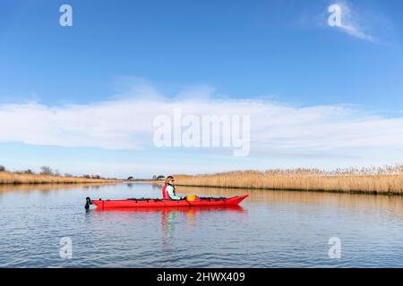 Woman by sea kayak explorign Isonzo river's mouth (Soča river) - Regional Nature Reserve of the Foce dell'Isonzo, Friuli Venezia Giulia region, Italy Stock Photo