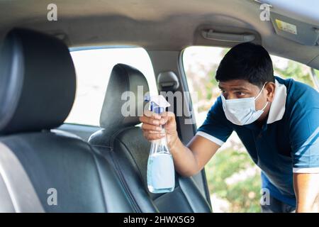 cab or car taxi driver with medical face mask sanitizing passenger seat - concept of coronavirus covi-19 safety measures, hygiene and medical Stock Photo