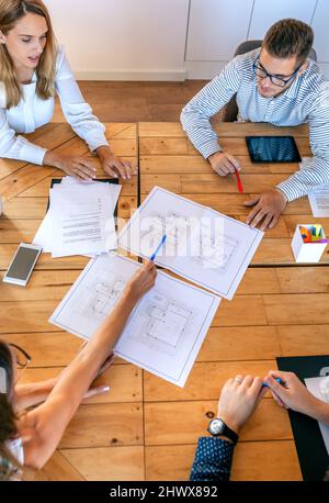 Top view of architects in a work meeting looking at construction drawings Stock Photo
