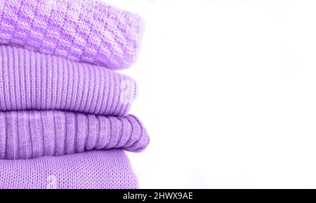 Stack of knitted warm purple sweaters isolated on white background. Copy space Stock Photo