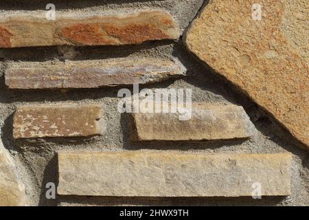 close up of stone garden wall structure. Close-up of a rustic stone wall with irregular slate tiles and textured mortar Stock Photo