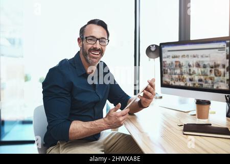 He moving forward in his career. Shot of a mature businessman using his digital tablet while sitting at his desk. Stock Photo