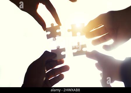 Finding the right fit. Cropped shot of four people holding puzzle pieces together. Stock Photo