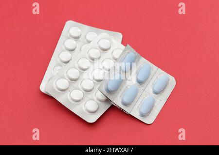 Colorful of tablets and capsules pill in blister packaging arranged on the red background. Stock Photo