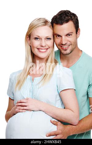 Looking towards the future. A smiling husband holding his pregnant wifes stomach from behind. Stock Photo