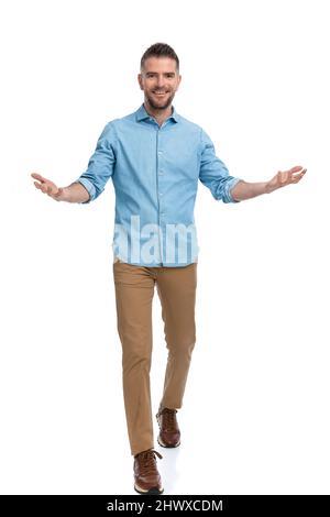 smiling man in denim shirt being happy, opening arms and welcoming on white background in studio Stock Photo