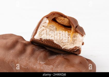 Two chocolate ice cream bars with caramel and peanuts on white background close up macro shot Stock Photo