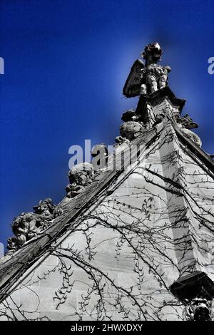 Old Gothic medieval gargoyle wearing a covid 19 pandemic face mask. Stock Photo