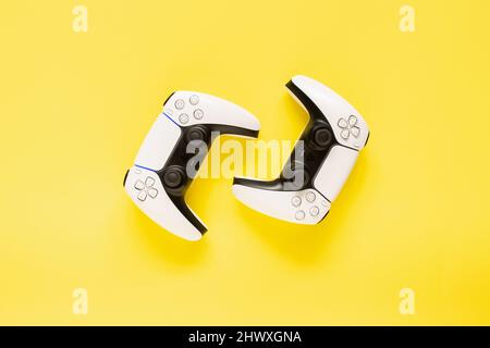 Ternopil, Ukraine - March 05, 2021: Two dualsense playstation 5 controllers on yellow background, gaming concept. Ps 5 gamepad Stock Photo