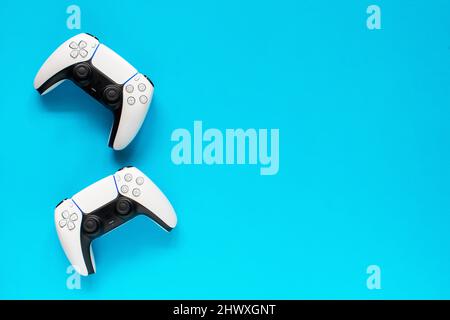 Ternopil, Ukraine - March 05, 2021: Two dualsense playstation 5 controllers on blue background, gaming concept. Ps 5 gamepad Stock Photo