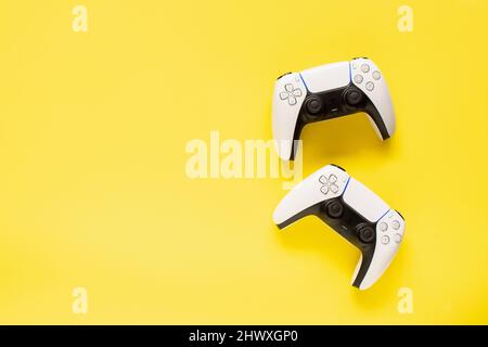Ternopil, Ukraine - March 05, 2021: Two dualsense playstation 5 controllers on yellow background, gaming concept. Ps 5 gamepad Stock Photo