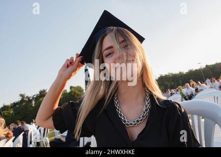 Graduduated student standing with cap. The girl graduated from university and she is so happy and proud. Bachelor's degree. Educational achievement. Stock Photo