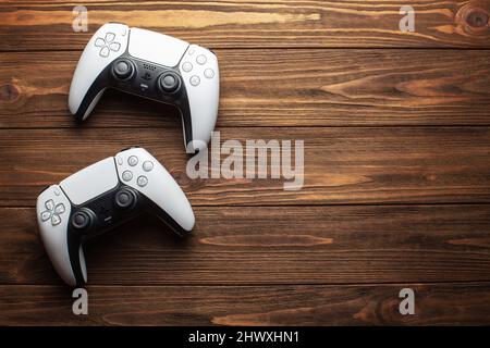 Two dualsense ps5 controllers on wooden background, gaming concept Stock Photo