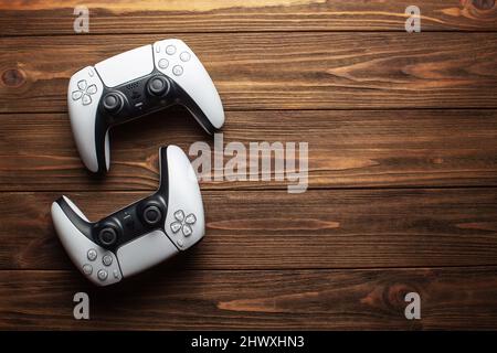 Two dualsense ps5 controllers on wooden background, gaming concept Stock Photo