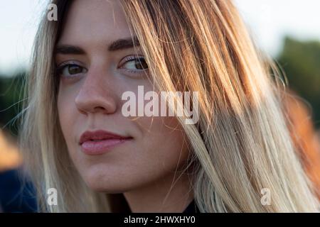 Portrait of a woman. Close up photo. She looks forward and smiling. Beauty sunshine girl side profile portrait. Pretty happy lady enjoying summer. Stock Photo