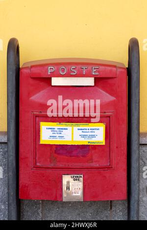Fossano, Cuneo, Italy - March 07, 2022: red mail box of the Italian Post office on a yellow wall with the times of the mail collection Stock Photo