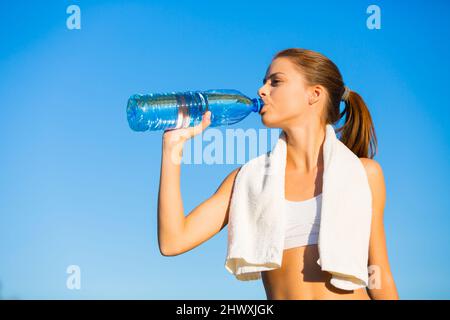 Rehydrating after a long workout. Shot of a beautiful young woman drinking water after her workout.