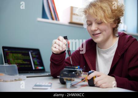 Teenage Girl With Laptop Building Robot On Desk In Bedroom At Home Stock Photo