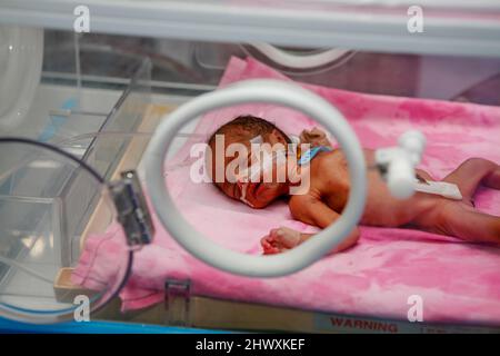 Premature baby in an incubator in the neonatal unit of a hospital. Premature babies are placed in incubator as they have not fully developed the mecha Stock Photo