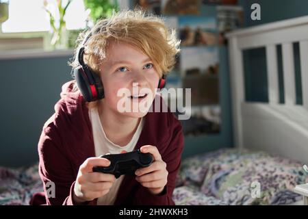 Excited Teeange Girl With Wireless Headphones Gaming Online In Bedroom At Home Stock Photo