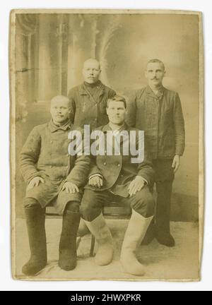 Original 19th century albumen print on card (small cabinet card size) probably Russian - this group of 4 working class / peasant class men are wearing typical felt boots of Russia, called Valenki, for hard work outside in the freezing cold. Circa 1880's /1890's, Russia. Stock Photo