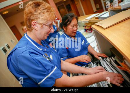 Two hospital nurses in dark blue uniforms filing patient notes in a London hospital.(MODEL RELEASED) Stock Photo
