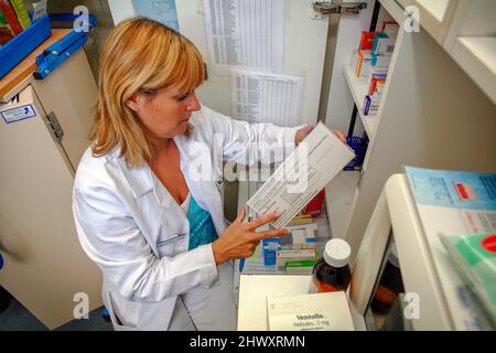 A female pharmacist reads the information label on the side of a mediction packet.(MODEL RELEASED) Stock Photo