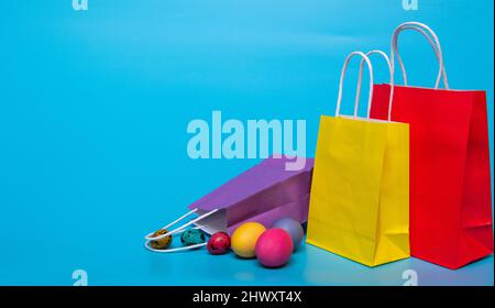 colored eggs and several paper bags on a blue background Stock Photo