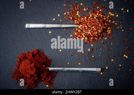 Spicy food, tasty exotic seasoning and assorted spice concept theme with a teaspoon of crushed red pepper powder and a spoon of parika Stock Photo