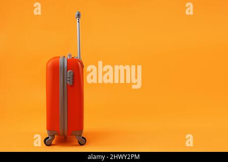Orange suitcase of travel bags on a yellow background with copy space. The concept of summer time, vacation, tourism. Stock Photo