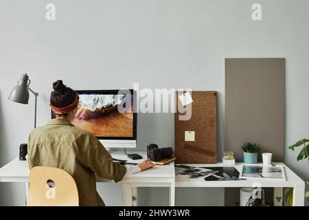 Minimal back view of female photographer editing photos at workplace in studio, copy space Stock Photo