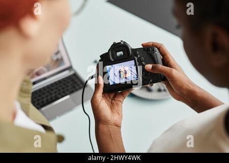 Top view close up of female photographer holding camera and looking at pictures on food on screen, copy space Stock Photo