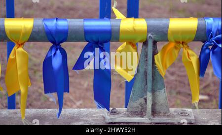 Ribbons in the colours of the Ukrainian flag, blue and yellow, tied to a pole to protest about the Russian invasion and war in Ukraine Stock Photo