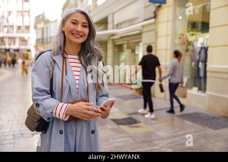 Trendy Asian woman walking outdoors in town Stock Photo