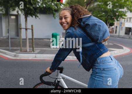 Portrait of smiling african american young woman riding bicycle in city Stock Photo