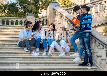 Group of young multiracial students talking on some stairs Stock Photo