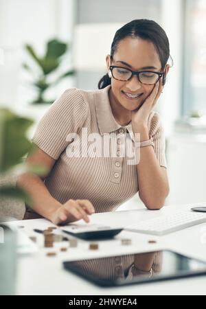 The key to successful economising is in setting goals. Shot of a young businesswoman calculating finances in an office. Stock Photo