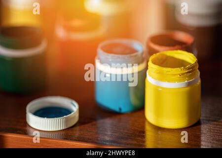 Jars of colorful paint for drawing are on desk. Bright gouache or watercolor paint. Background. Stock Photo
