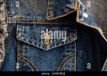 Dark-colored denim jacket pocket close-up. Denim with stitching and seam. Background. Stock Photo