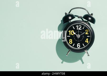Black alarm clock with yellow numbers on light colored background. Time to think or time to negotiate. Concept. Copy space. Stock Photo