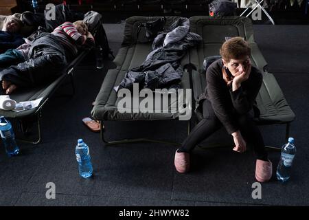 Krakow, Poland. 08th Mar, 2022. A women seen sitting on the camp-bed in the sports hall of the Cracovia club where accommodation was organised for refugees from Ukraine coming to Krakow. Credit: SOPA Images Limited/Alamy Live News Stock Photo